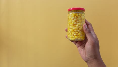 handheld jar of canned corn