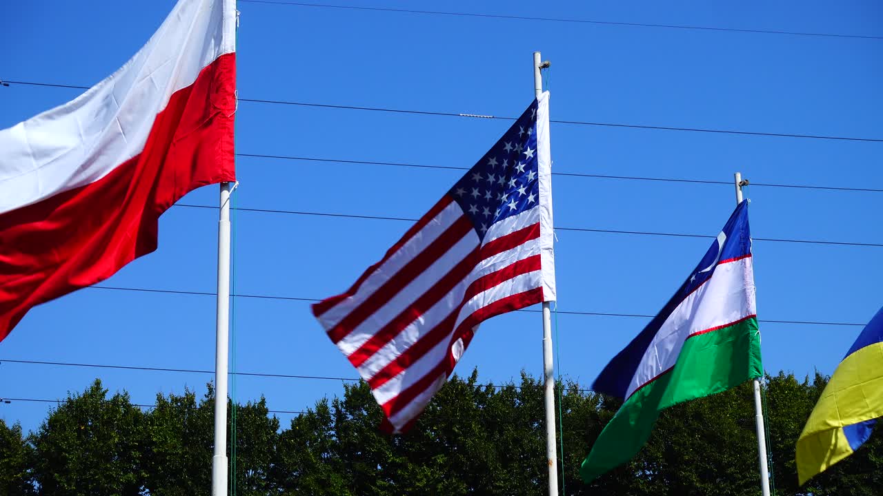 Flags of Poland, USA, Uzbekistan and Ukraine on flagpoles