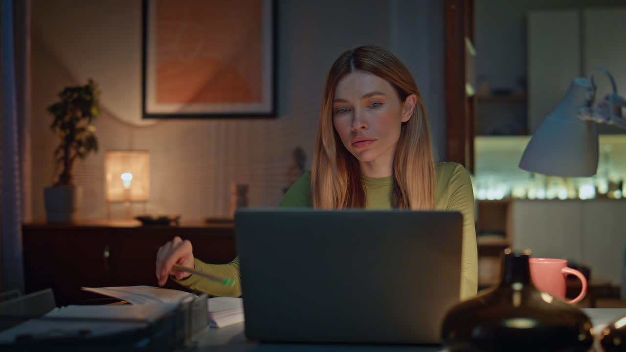 Serious freelancer work online in dark apartment close up. Woman making notes