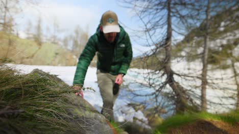 Slow-motion-hiker-climbs-up-snow-covered-trail-near-mountain-stream