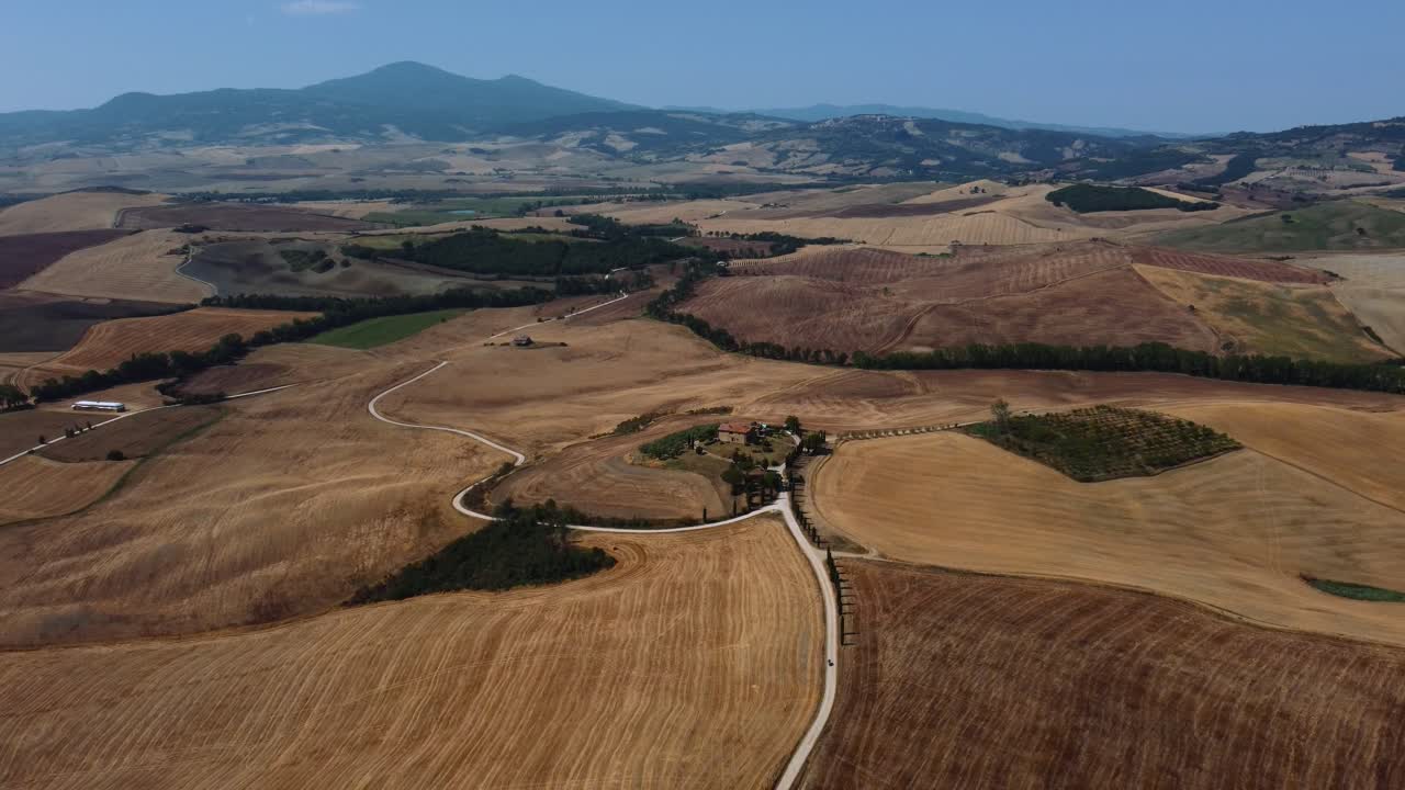 ubicación de la película aérea del gladiador protagonizada por russell crowe en val d'orcia cerca de siena, florencia y pienza con una avenida de cipreses con campos de cultivo de trigo cosechados en colinas panorámicas de verano