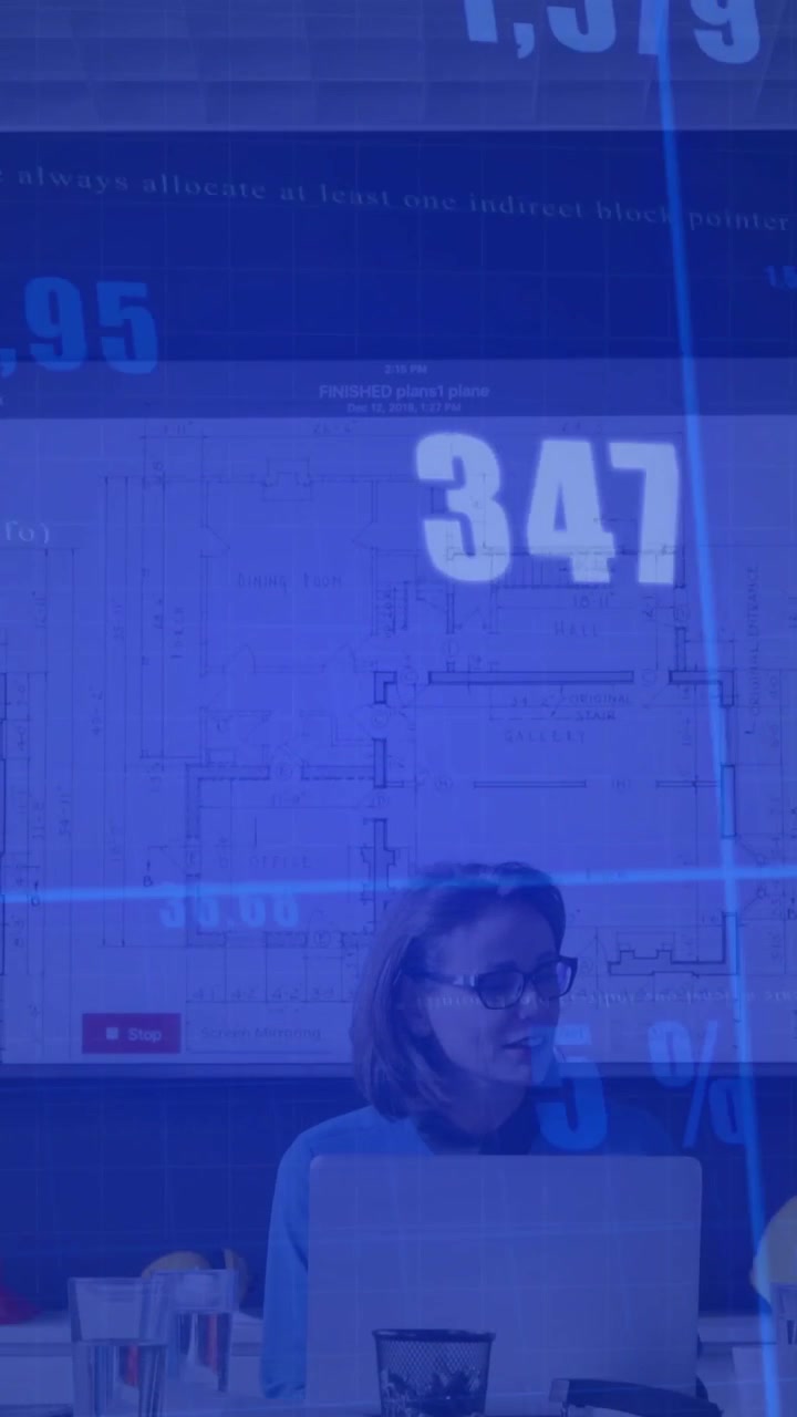 Video verticale: Donna con maglietta blu e occhiali che si gira di fronte allo schermo dell'ufficio mentre l'HUD si sposta, con un laptop.