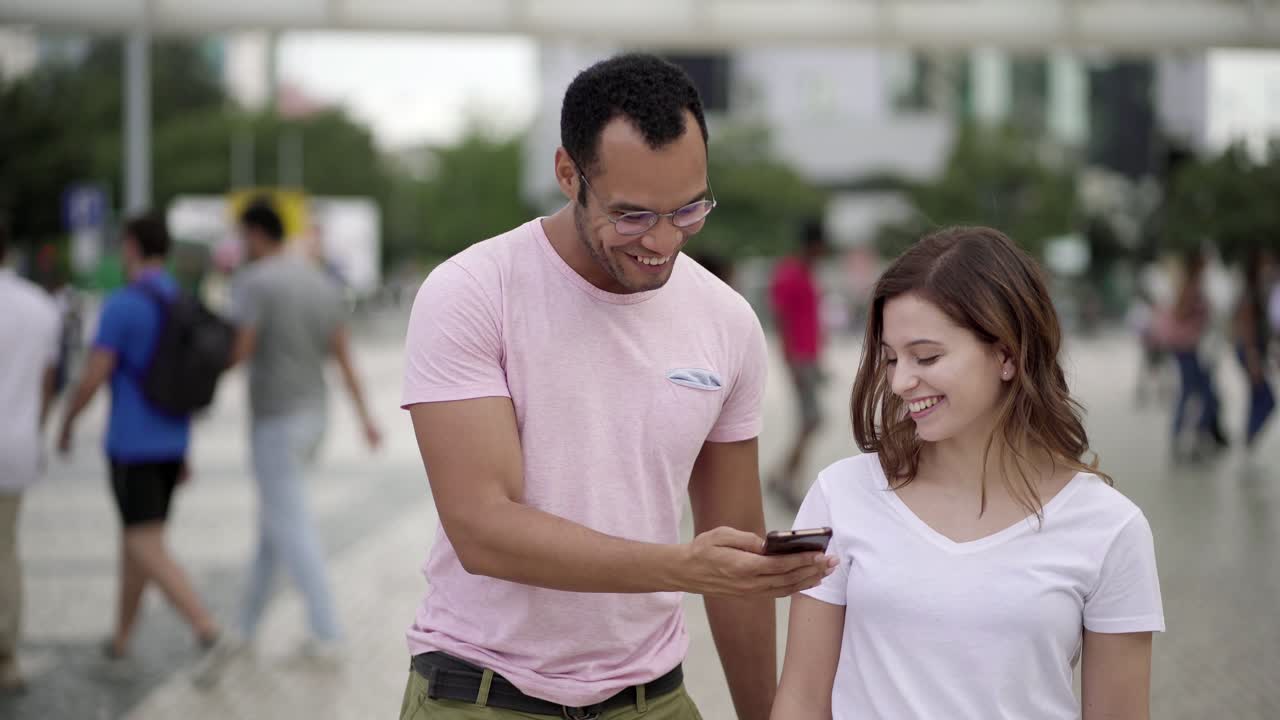 una joven pareja sonriente mirando un teléfono inteligente