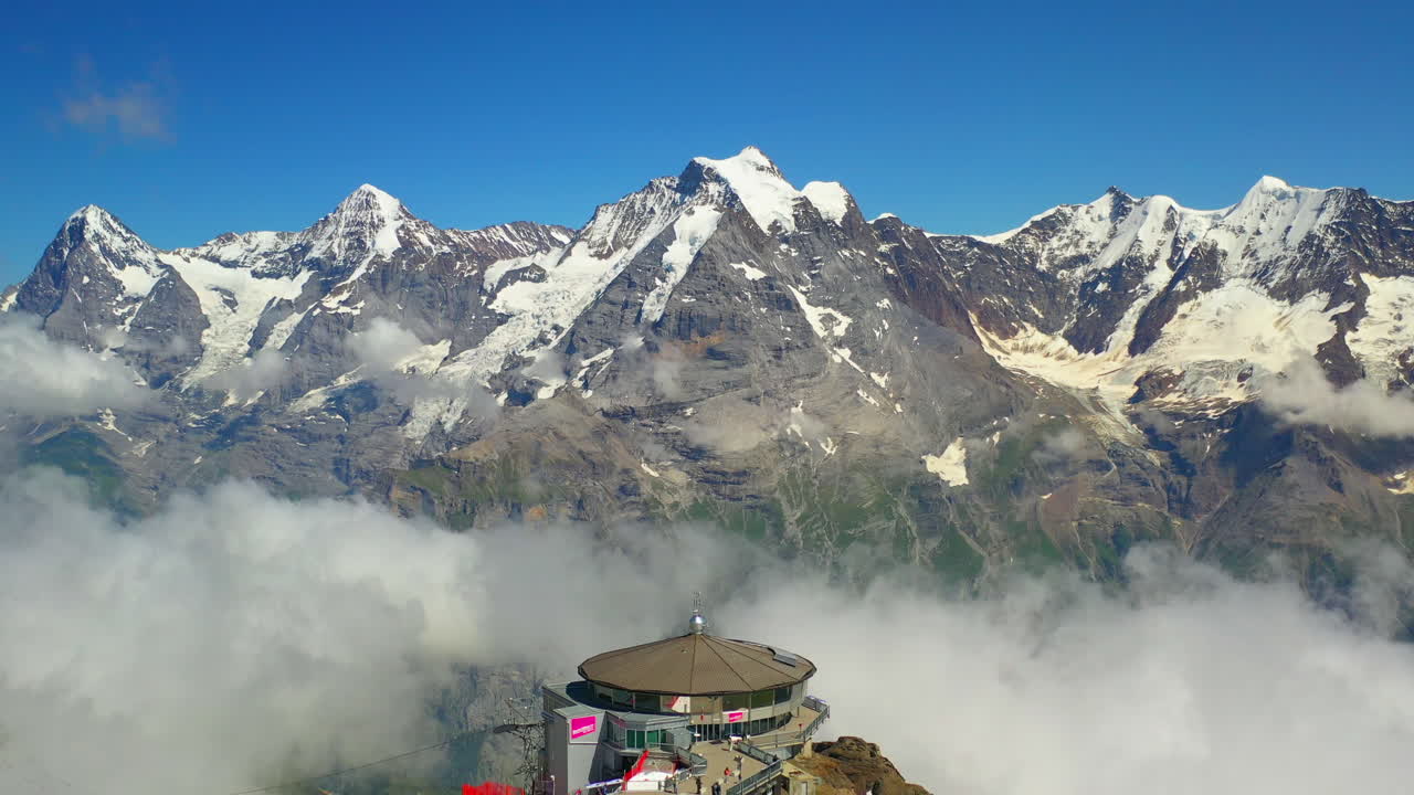 Drone shot starting on the Schilthorn summit then revealing Piz Gloria the rotating restaurant