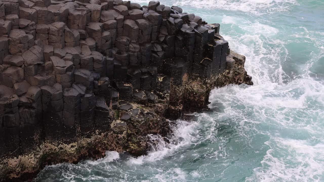 Dynamiske havbølger der rammer en basaltklippeformation
