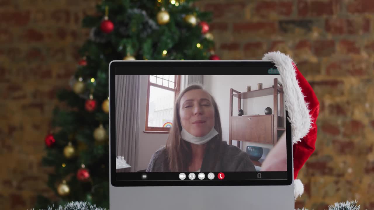 mujer mayor caucásica feliz en videollamada en el monitor de la computadora, con árbol de navidad