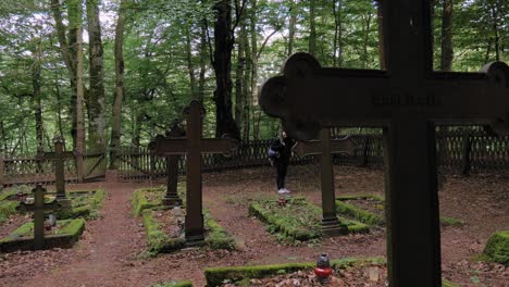 a female traveler visiting the forest ranger cemetery nestled in lush hill of pyszno, northern poland - medium shot