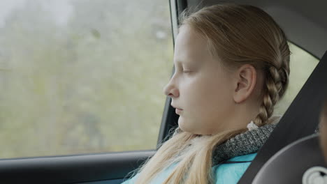 a girl of ten years old rides in the back seat of a car