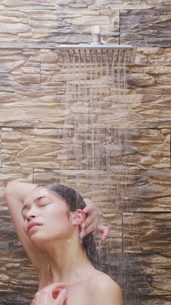 video vertical de una mujer biracial tomando una ducha en el baño