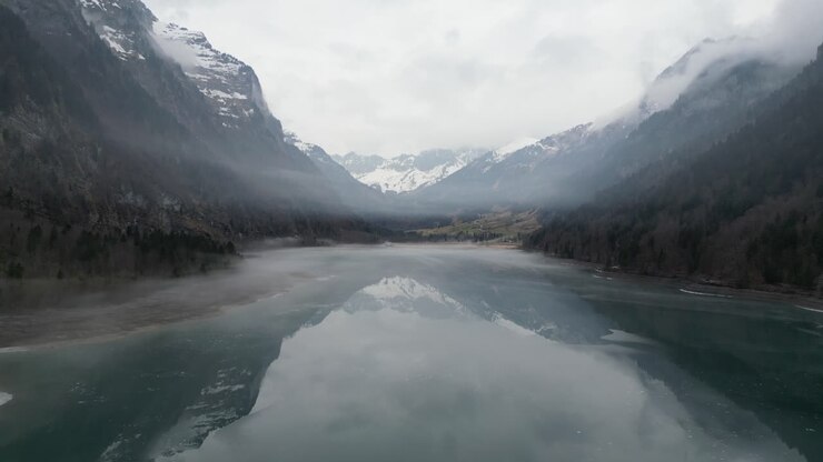 Klöntalersee Glarus Svizzera, bellezza serena volando sotto la nebbia sopra un lago a specchio.