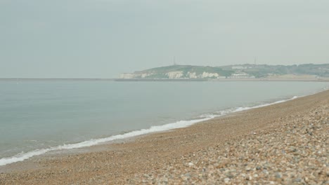 Slowmotion-shot-of-the-pebble-sandy-coast-of-Seaford-with-rocks-in-the-foreground