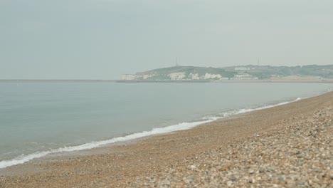 slowmotion shot of the pebble sandy coast of seaford with rocks in the foreground