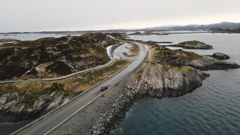 bmw car drives on the atlantic ocean road with tourists walking at eldhusoya national scenic routes around the island in norway