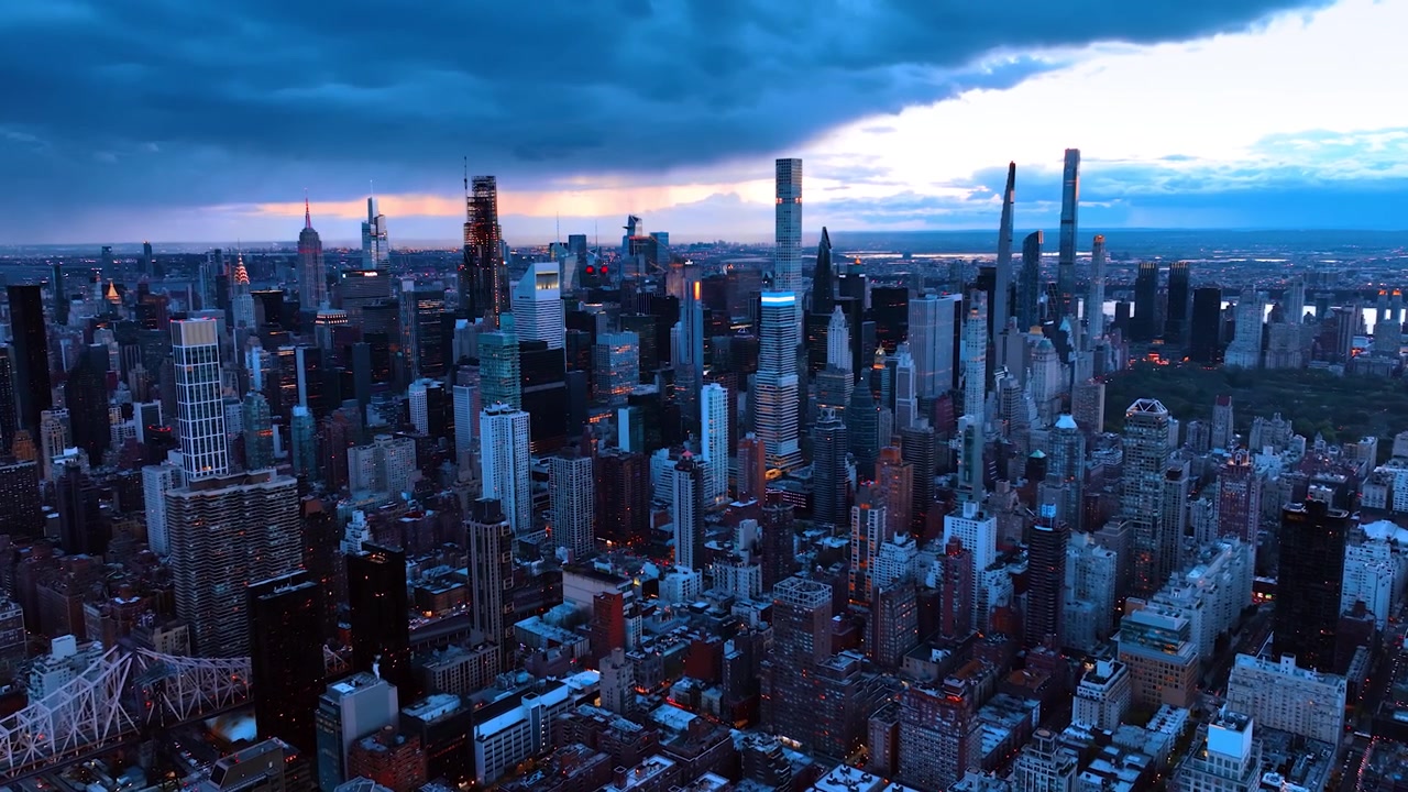 Multiple skyscrapers in the panorama of New York, the USA at the backdrop of cloudy sky. Twilight view of the modern metropolis from top.