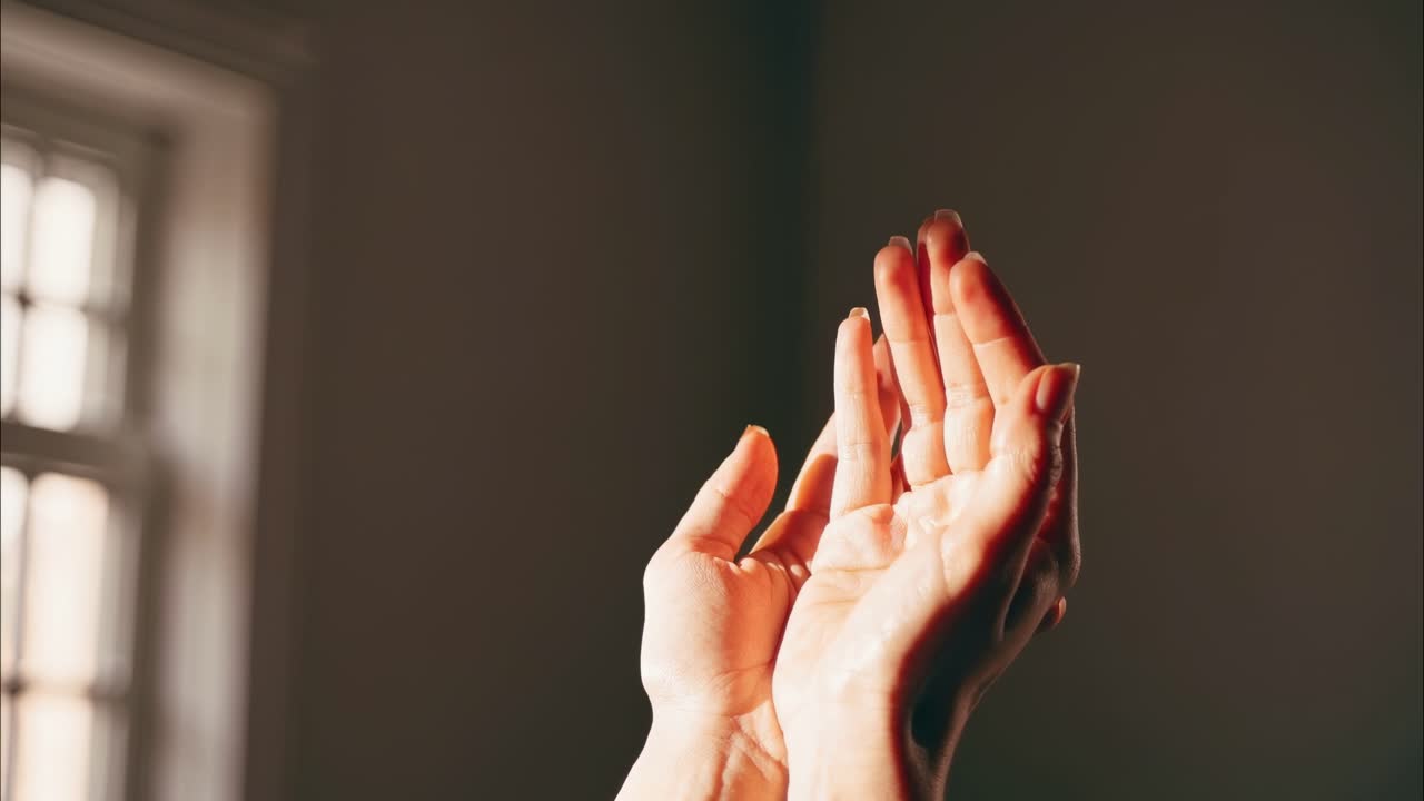 Close-up video of hands in prayer position, captured from a low angle