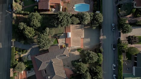 aerial establishing shot above green european neighborhood houses, streets swimming pools, roads and tile red roofs