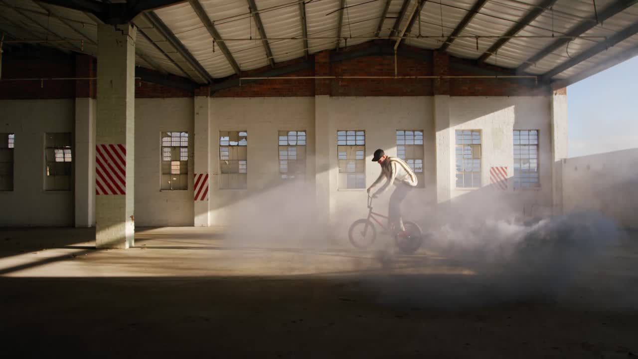 jinete de bmx en un almacén vacío usando una granada de humo