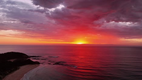 stunning aerial pullback of a sunrise over inyadda beach, nsw, australia, with glowing clouds above