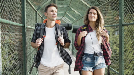 pareja de viajeros con mochilas caminando por el puente