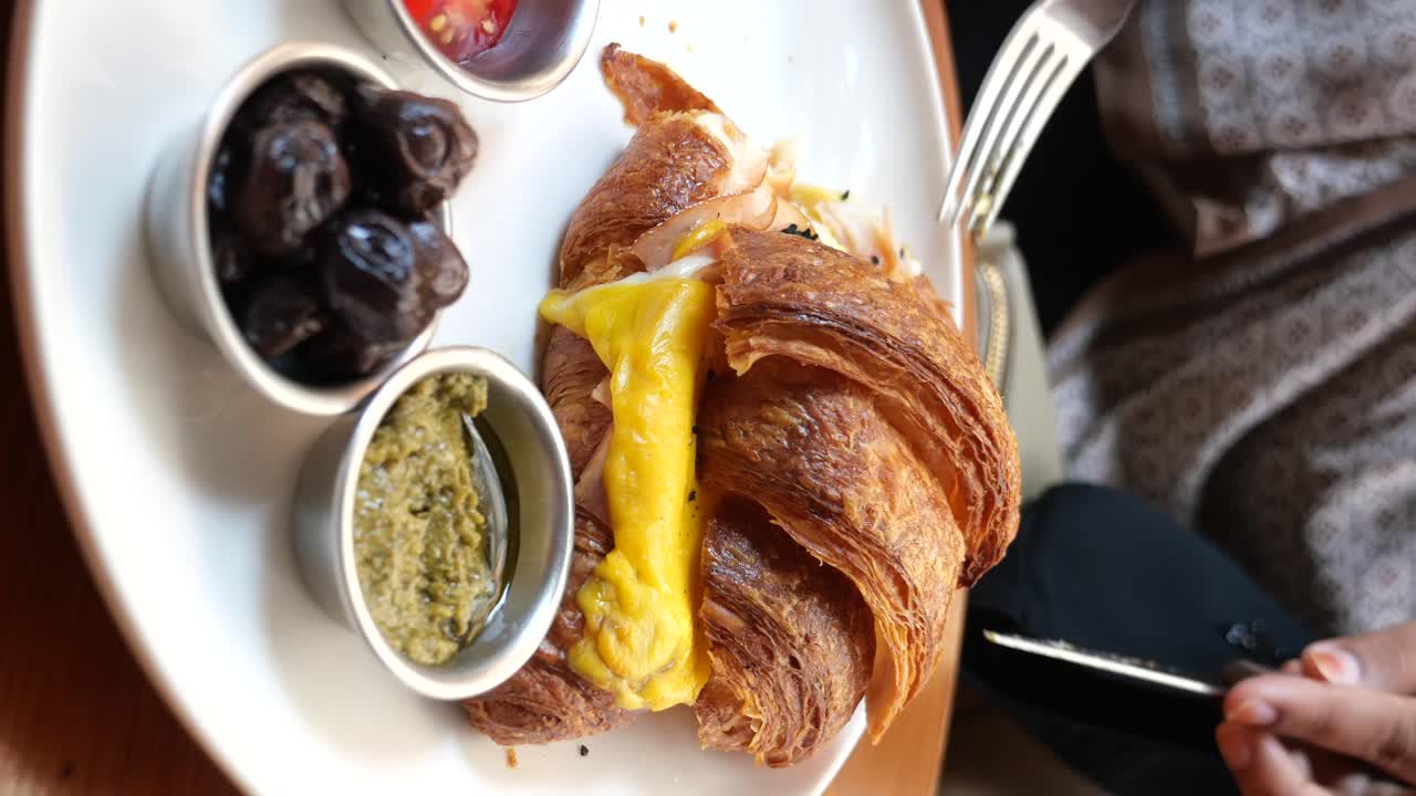 Croissant breakfast with olives, pesto, egg and tomato