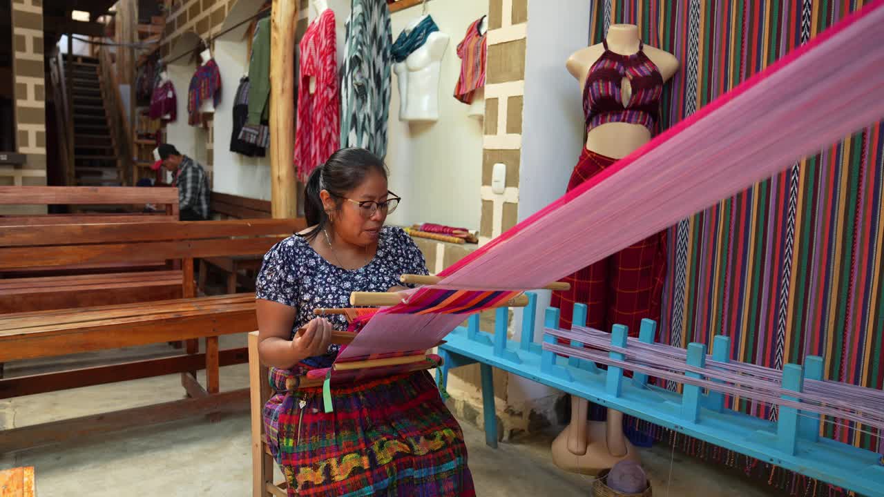 video de una mujer haciendo textiles tradicionales guatemaltecos a mano usando telares de espalda y pedales.