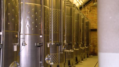 a shot of a winery wine cellar with large steel barrels storing wine