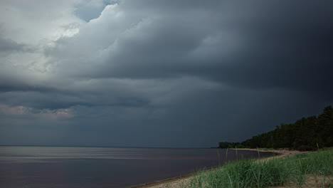 Storm-clouds-roll-in-tumultuously-across-shoreline-beach-forest-as-people-walk