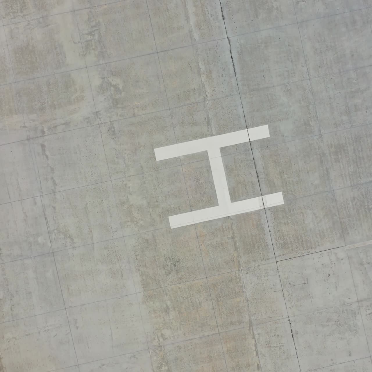 Empty parking space. Square place for parking cars with the letter H in the center. Modern parking on field. Top aerial view. Motion down