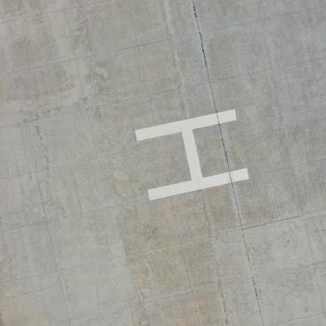 empty parking space. square place for parking cars with the letter h in the center. modern parking on field. top aerial view. motion down