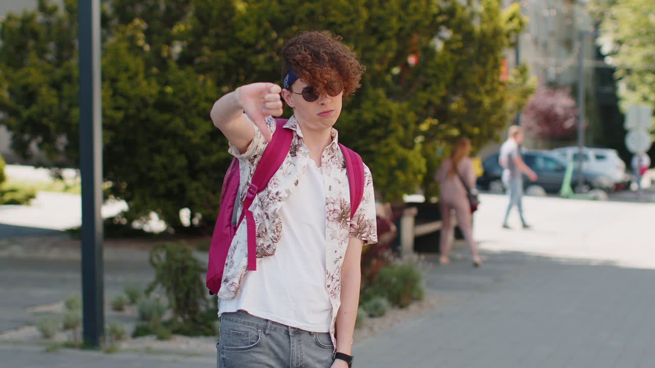 Upset tourist man in sunglasses showing thumb down dislike sign gesture disapproval dissatisfied