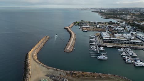 aerial establishing shot of boat leaving coogee port in perth city during cloudy day - forward flight