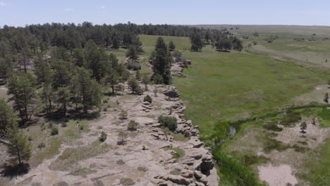 aerial views of a grassy plane heading to a beautiful rock formation in palmer lake colorado