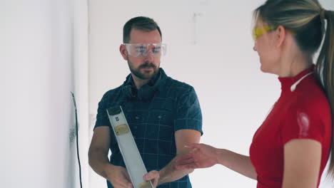 builder with level shakes hand of colleague in spacious room