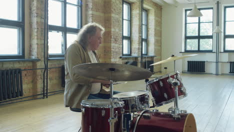 mature musician drumming in studio