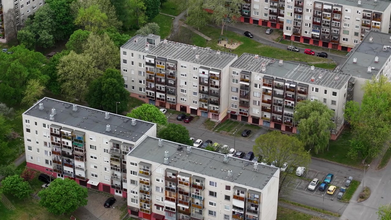 Een bovenaanzicht van residentiële appartementencomplexen omringd door groen in een rustige buitenwijk tijdens de lente