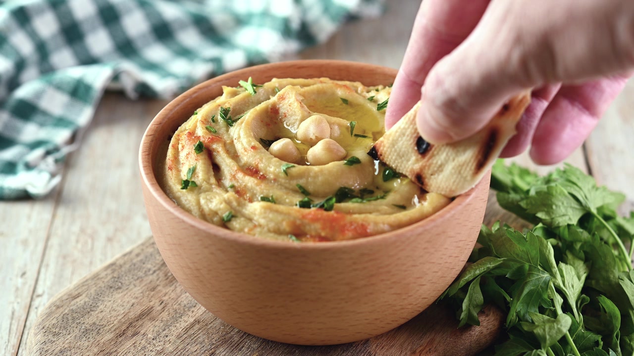 Uomo che intinge hummus di ceci
