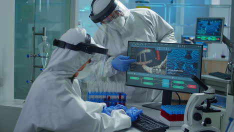 professional chemists in ppe suit analysing vaccine development pointing on pc