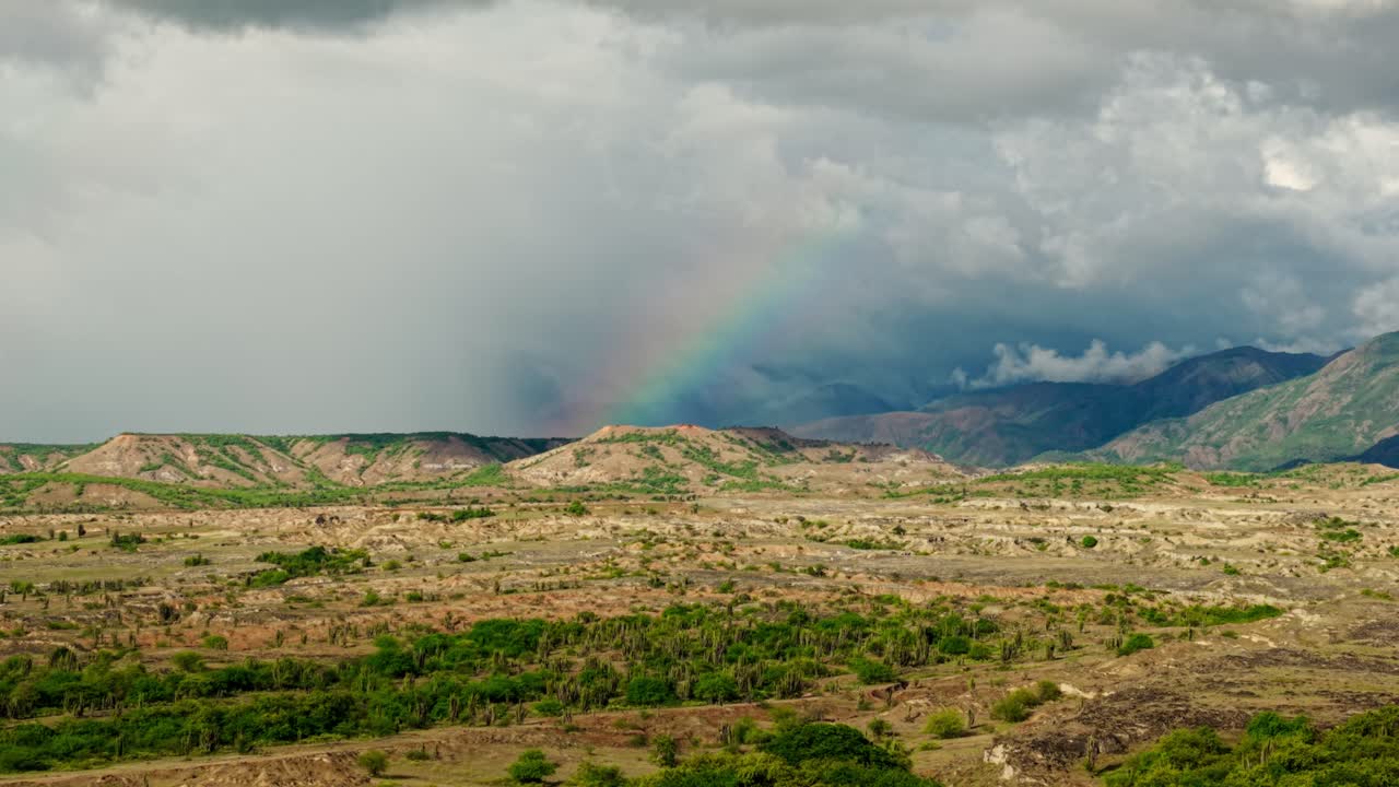 Naturskönt flygfoto över Tatacoaöknen i Colombia med en färgstark regnbåge under molniga himlar.