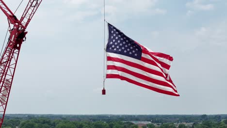 hung from a construction crane, the flag of the united states waves in the wind