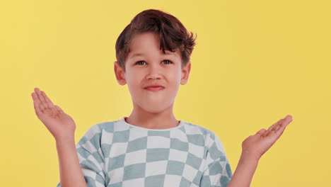 A young boy with hands up on a yellow background