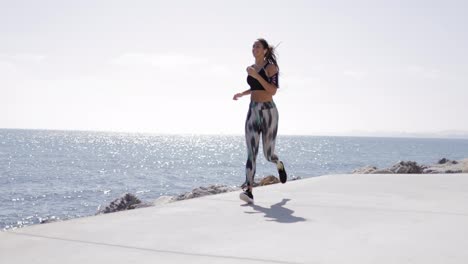 View-of-fit-girl-in-sportswear-running-along-seafront