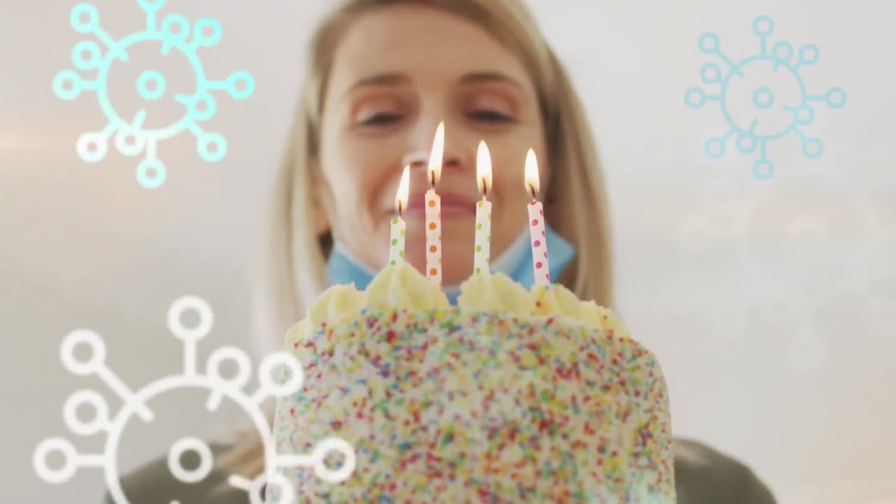 animación de las células del virus covid 19 sobre una mujer caucásica feliz que usa una máscara facial celebrando su cumpleaños