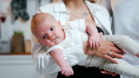 lovely red-haired newborn in mom's hands. calm baby boy with his parents at home. close up.