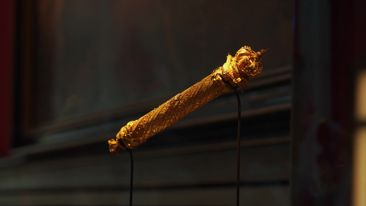 Nahaufnahme eines verzierten goldenen historischen Artefakts, ausgestellt unter warmer Museumsbeleuchtung, das detaillierte Metallarbeiten, Handwerkskunst und kulturelles Erbe zeigt.
