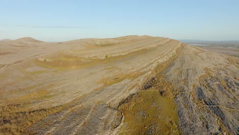 Stratigraphic-lines-sweep-up-along-limestone-hills-on-sunny-day-with-rock-walls-in-the-Burren-Ireland