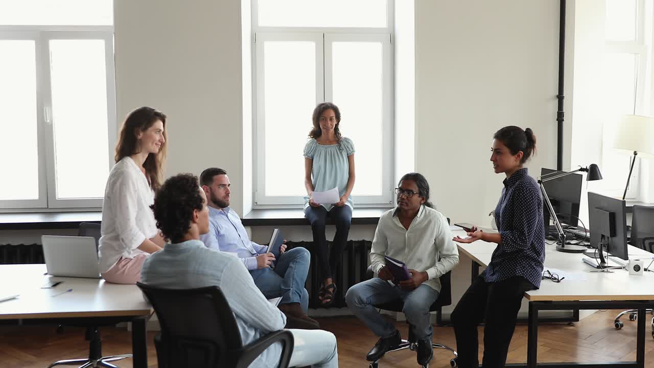 Indisk kvindelig kontormedarbejder og multikulturelle kolleger deltager i diskussion.