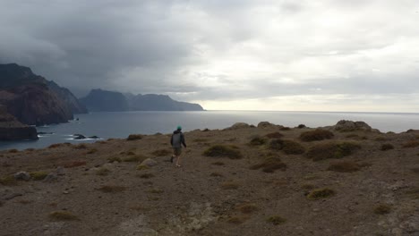 Aerial-is-following-a-young-man-that-is-running-towards-the-edge-off-the-cliff-at-Sao-Laurenco-in-Madeira