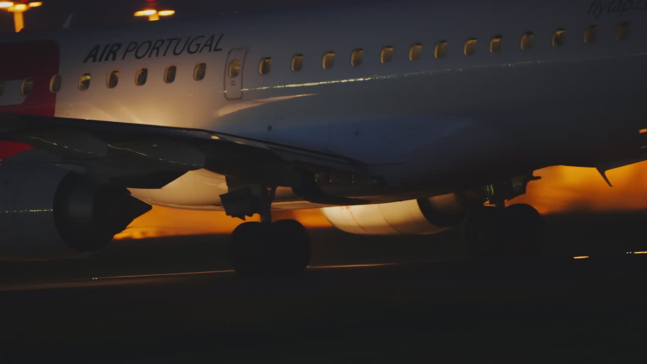 TAP Air Portugal cabin windows with passengers visible at night on apron
