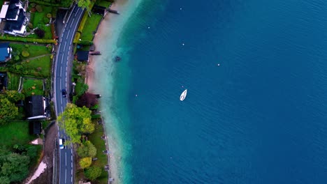 Luftaufnahme-Einer-Straße-Und-Eines-Kleinen,-Weißen-Segelboots,-Das-In-Einer-Türkisfarbenen-Bucht-Mit-Weißen-Sandstränden-Und-Palmen-Vor-Anker-Liegt,-Umgeben-Von-üppigem-Grün