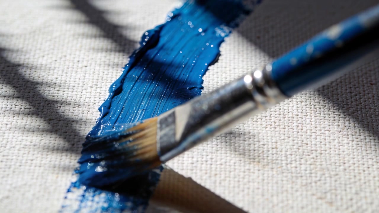 Touching flat paintbrush ferrule laying navy paint on canvas at studio forming stripe under blinds
